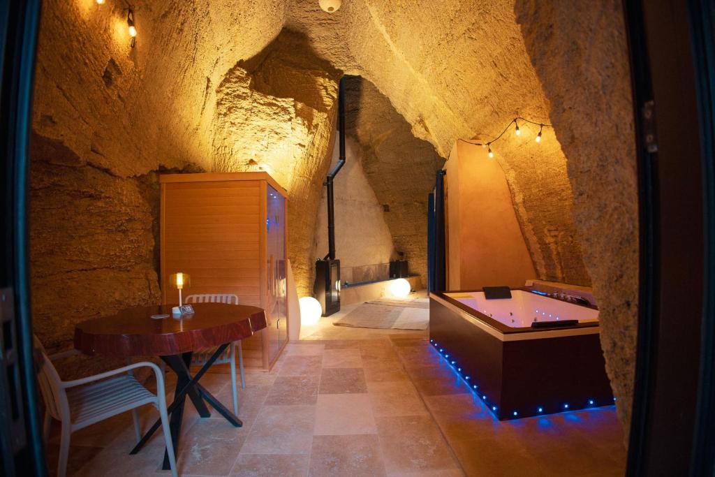 a room with a table and a tub in a cave at L'Escapade in Baugé