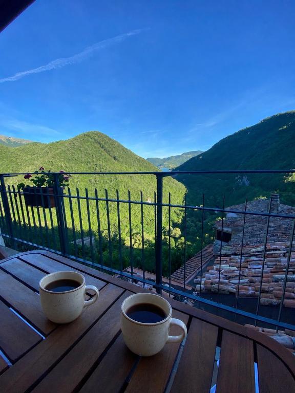 two cups of coffee sitting on a wooden table on a balcony at La casina di Viola in Posticciola