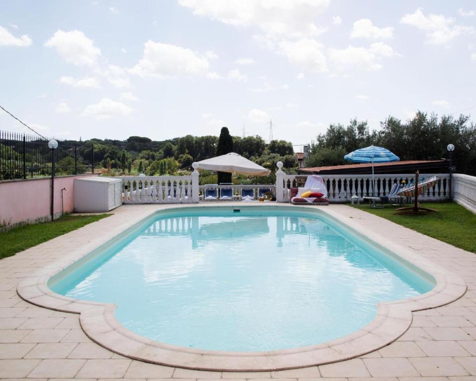 a large swimming pool with blue water in a yard at Villa Ennio in Ciampino