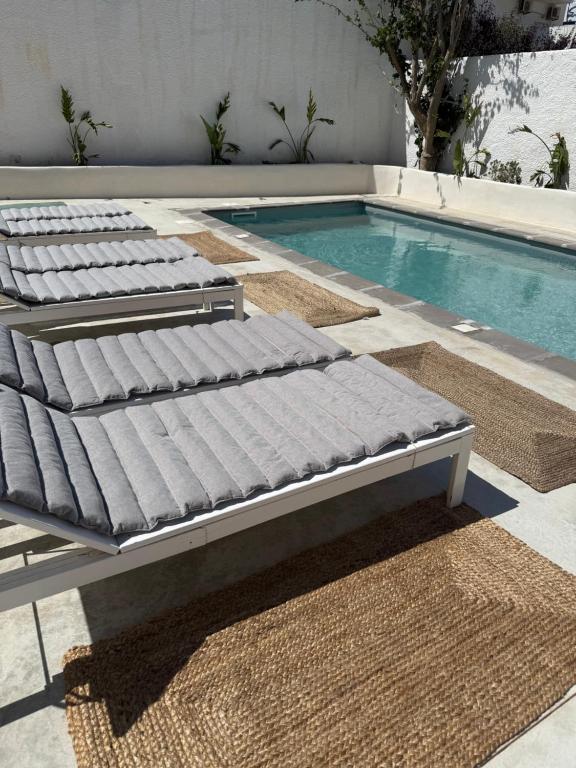a row of beds next to a swimming pool at Tinion Hotel in Tinos