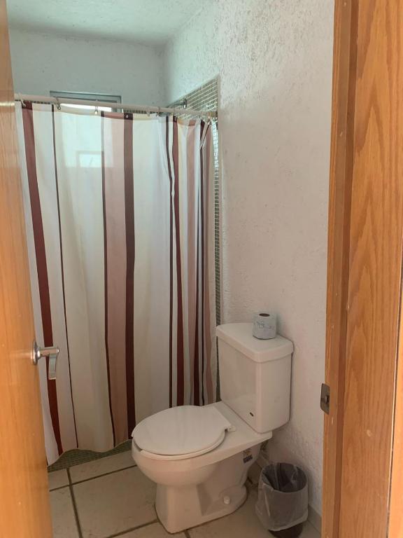 a bathroom with a toilet and a shower curtain at Casa Tikul in Temixco
