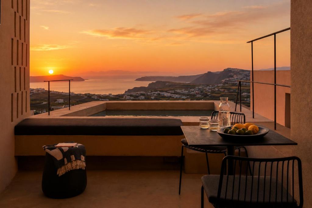 a room with a bed and a table with a bowl of fruit at Enorme EOS Santorini - Adults Only in Pyrgos