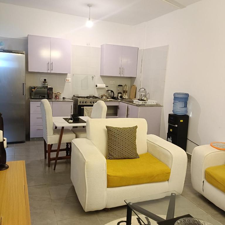 a living room with a white couch and a kitchen at Zurilyn Crib in Malindi
