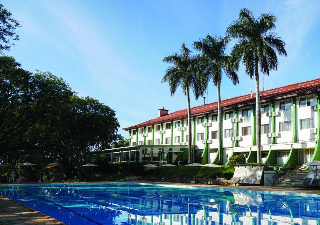 a hotel with palm trees and a swimming pool at Itapura Eco Resort in Atibaia