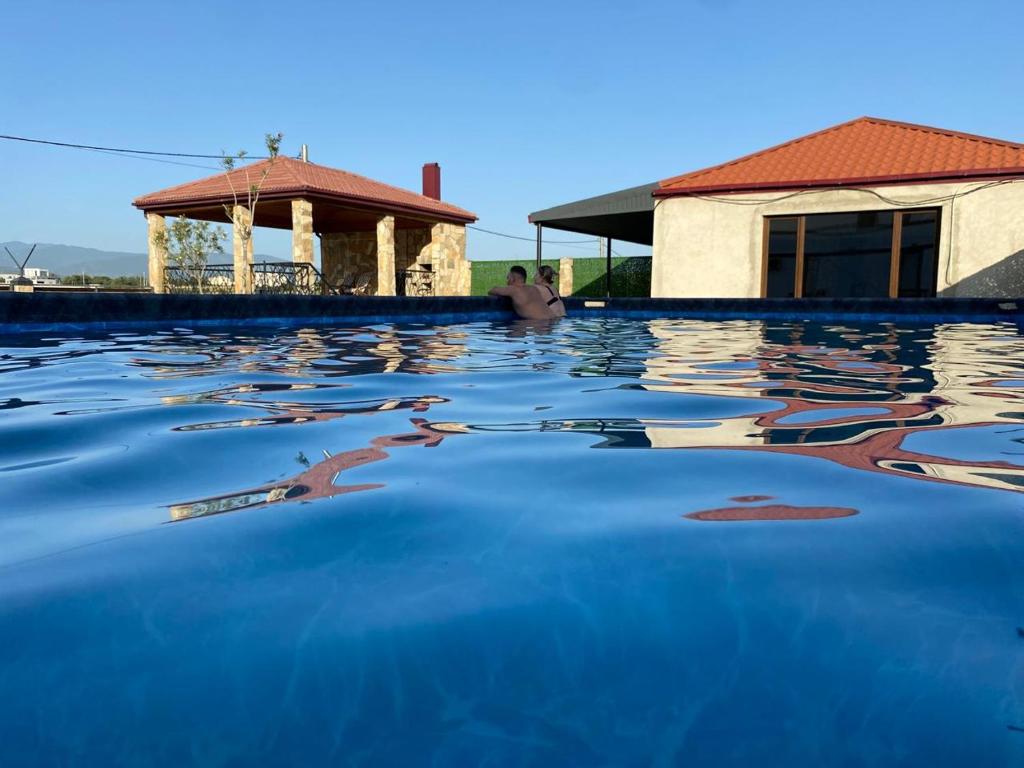 a man sitting in a swimming pool next to a house at Pura Vida Boutique Hotel Tbilisi in Tbilisi City