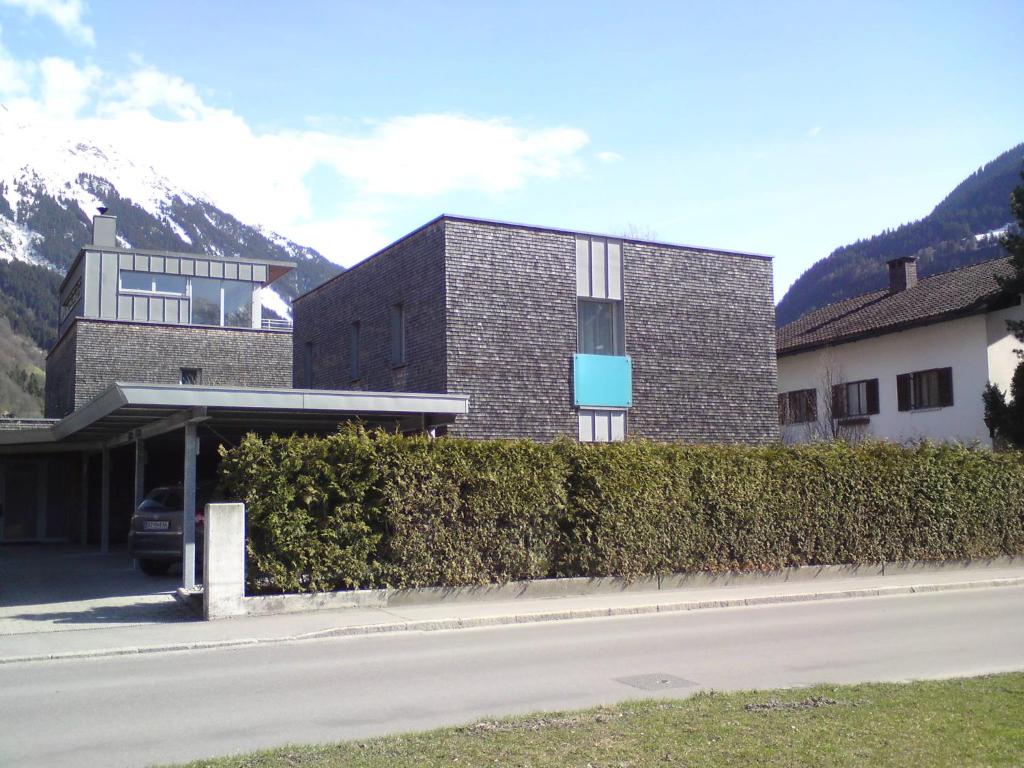 a building with a hedge in front of a street at Ferienhaus Stemer Montafon in Schruns