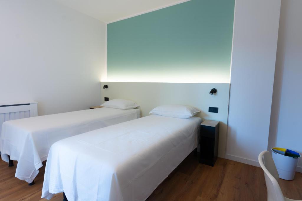 two beds in a room with white walls and wooden floors at Bed & Bricks in Reggio Emilia