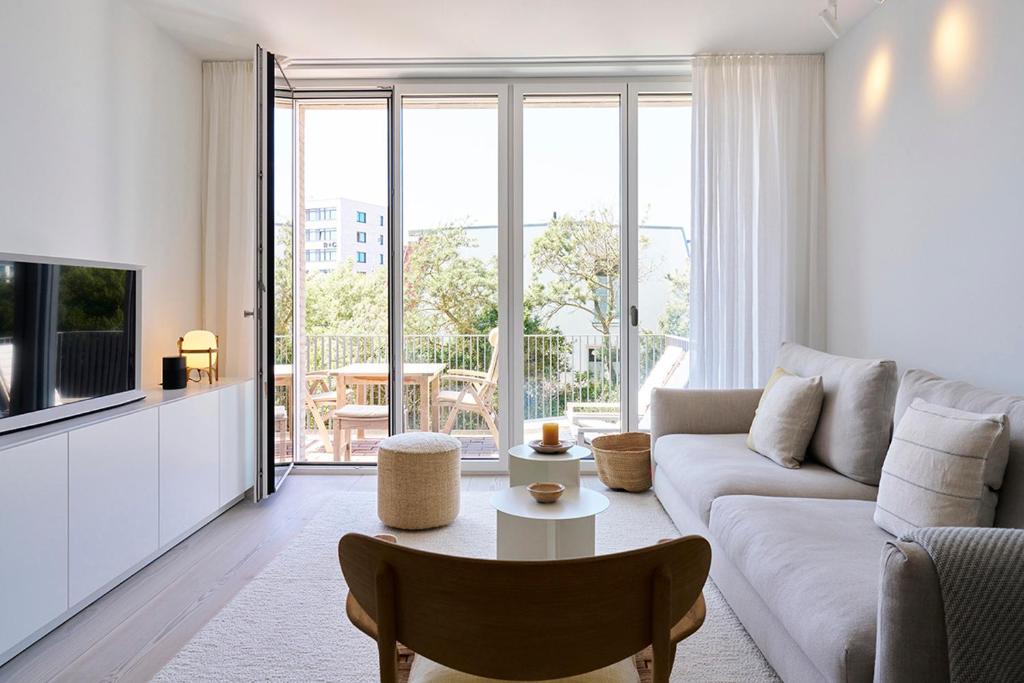 ein weißes Wohnzimmer mit Sofa und Fernseher in der Unterkunft Inselhouse in Norderney