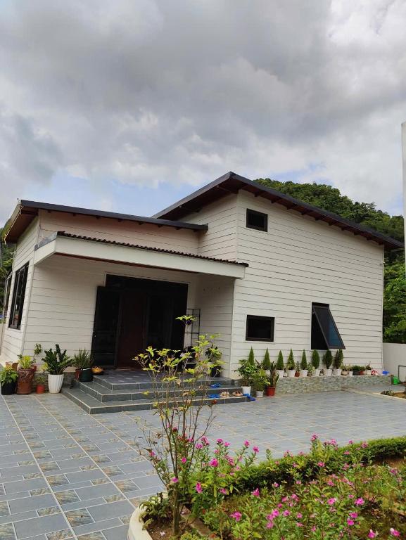 a white building with a lot of plants in front of it at CoNa Homestay in Ðồng Khê Sâu