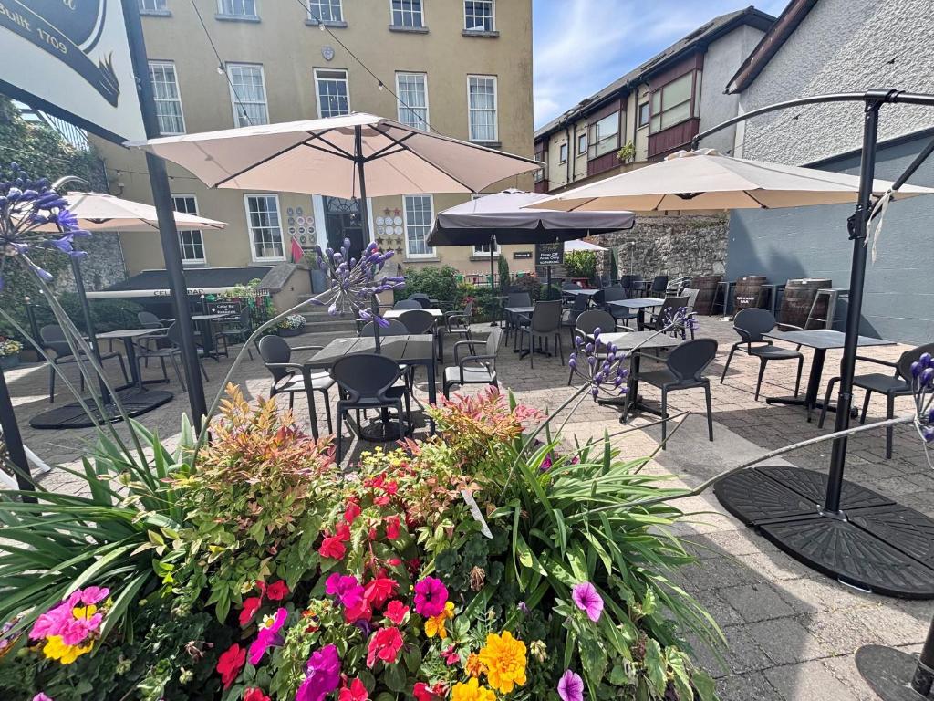 a patio with tables and chairs with flowers and umbrellas at Baileys Hotel Cashel in Cashel