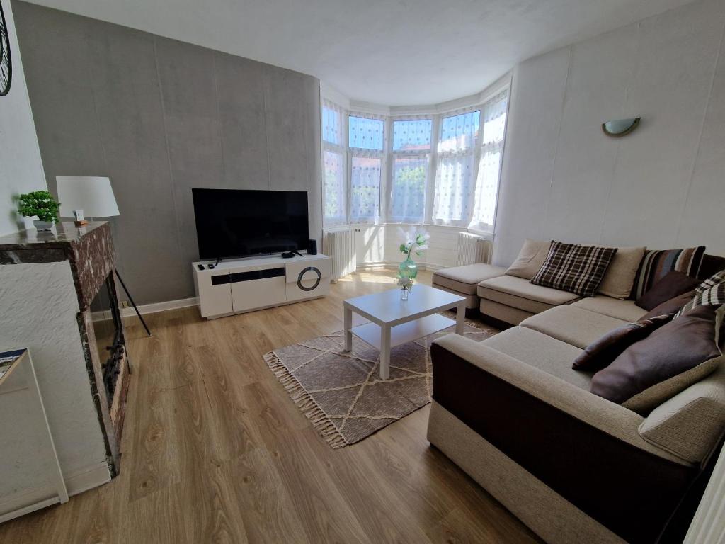 a living room with a couch and a tv at Spacieux duplex familial proche Dunkerque et plage in Coudekerque-Branche