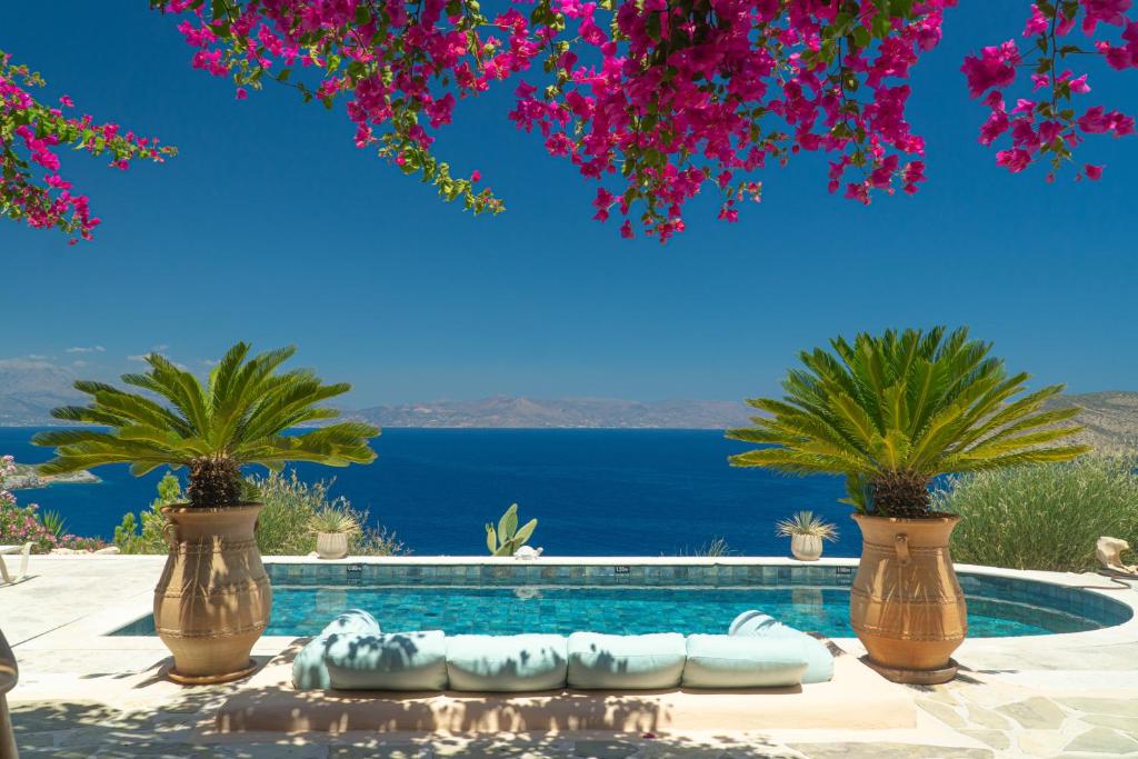 a pool with a view of the ocean and palm trees at Villa Mirabello Tholos Adults Only in Kavoúsion