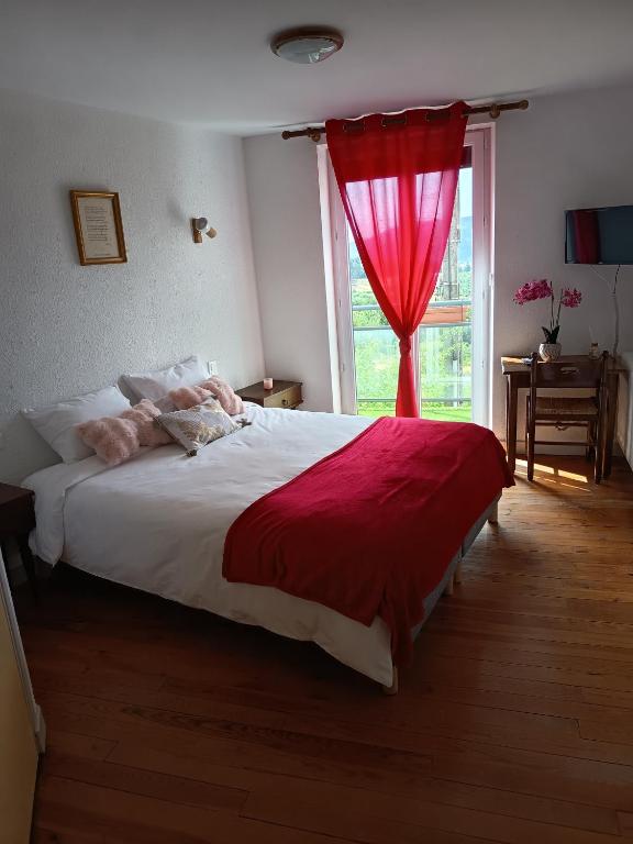 a bedroom with a large bed with a red curtain at Auberge de la Belette in Le Monestier