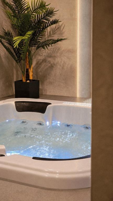 a bath tub filled with blue water in a bathroom at Luxury wellness apartment SHA in Osijek