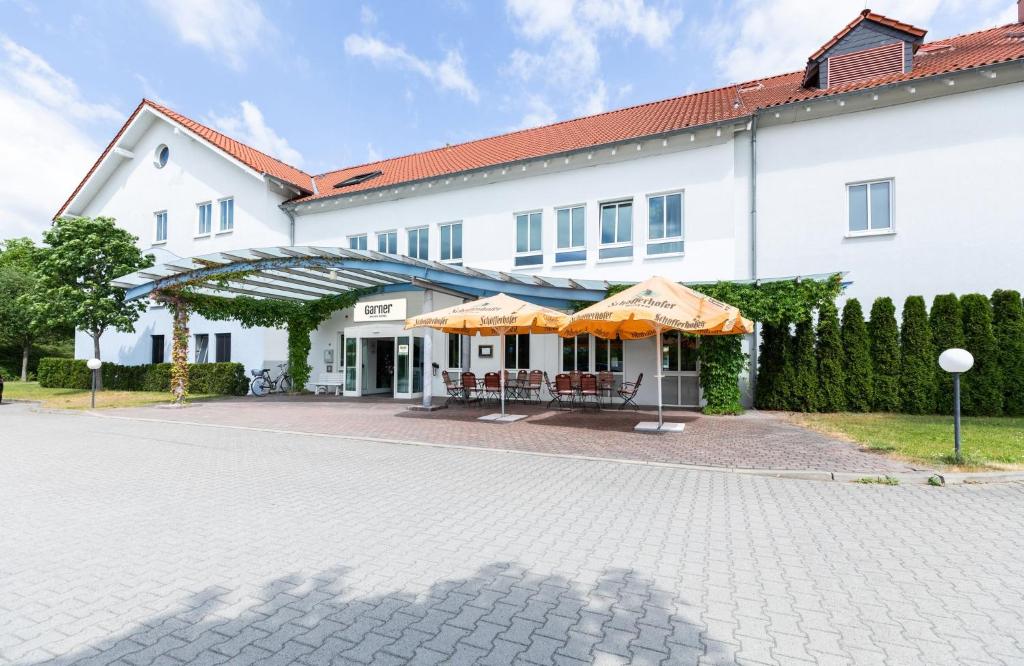 a large white building with umbrellas in front of it at Garner Hotel Cottbus Süd by IHG in Cottbus