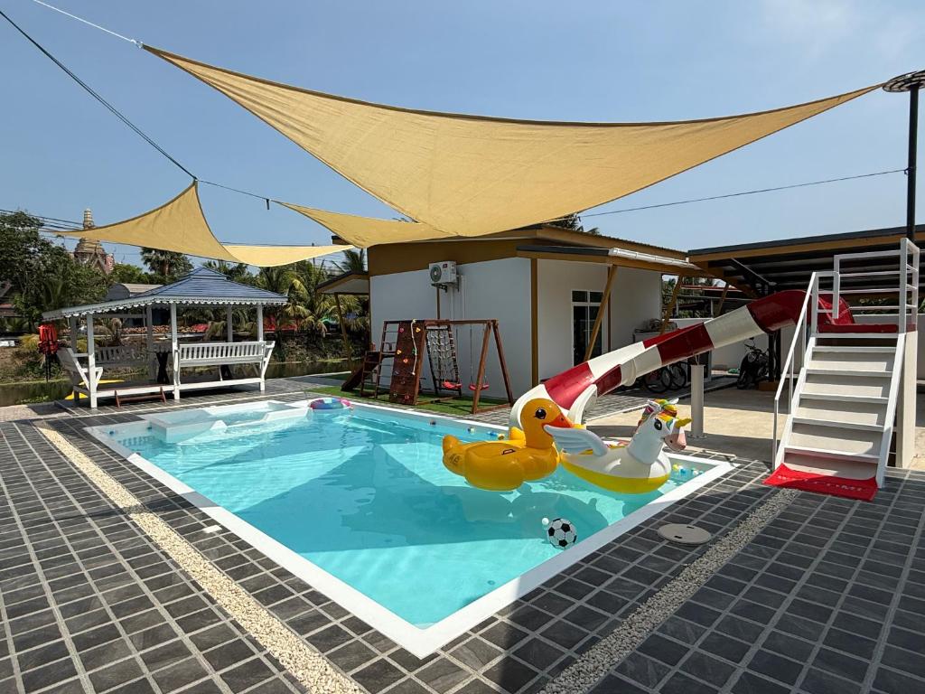 a swimming pool with two rubber ducks and a slide at My friend private pool villa in Samut Songkhram