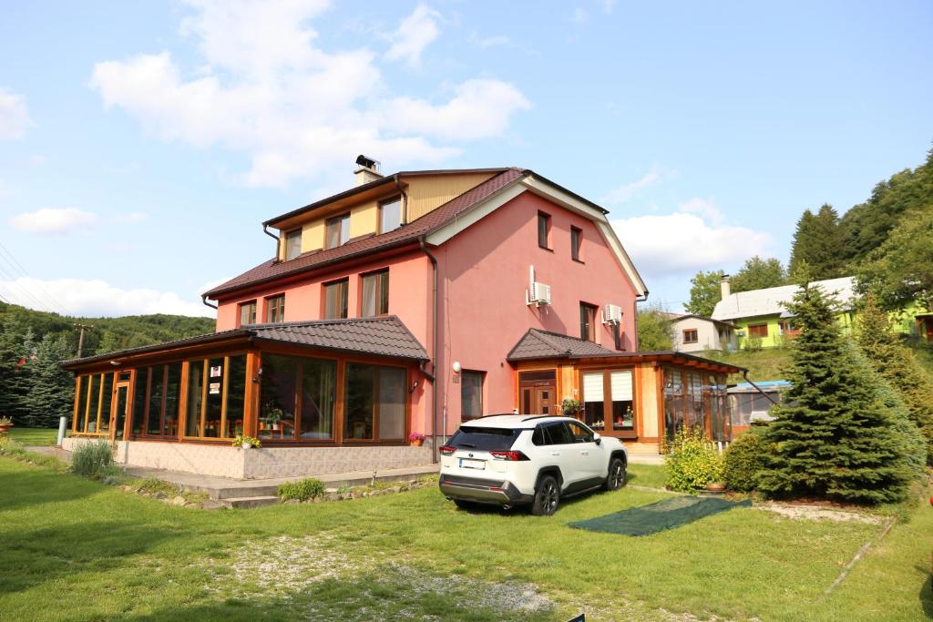 a car parked in front of a pink house at Penzion Chřiby in Staré Hutě
