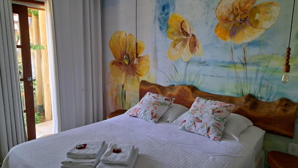 a bedroom with a white bed with flowers on the wall at Dona Maragô Pousada in Maragogi
