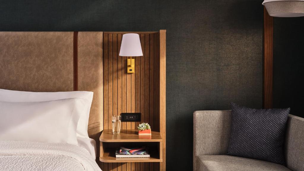 a bedroom with a bed and a chair and a lamp at Holiday Inn & Suites Tijuana Downtown by IHG in Tijuana