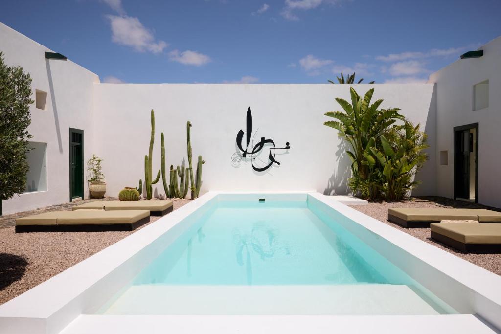 a pool in the backyard of a house with cactus at Casa Montelongo - Adults Only in La Oliva