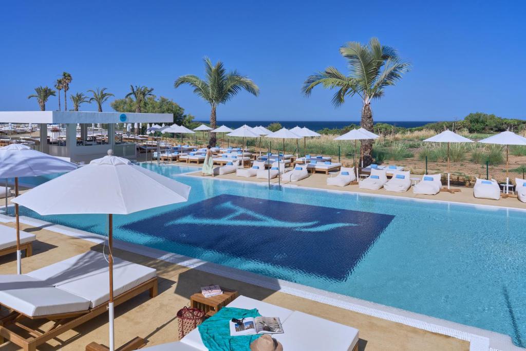 a pool with lounge chairs and umbrellas at a resort at Amare Beach Hotel Sancti Petri - Adults Recommended in Chiclana de la Frontera