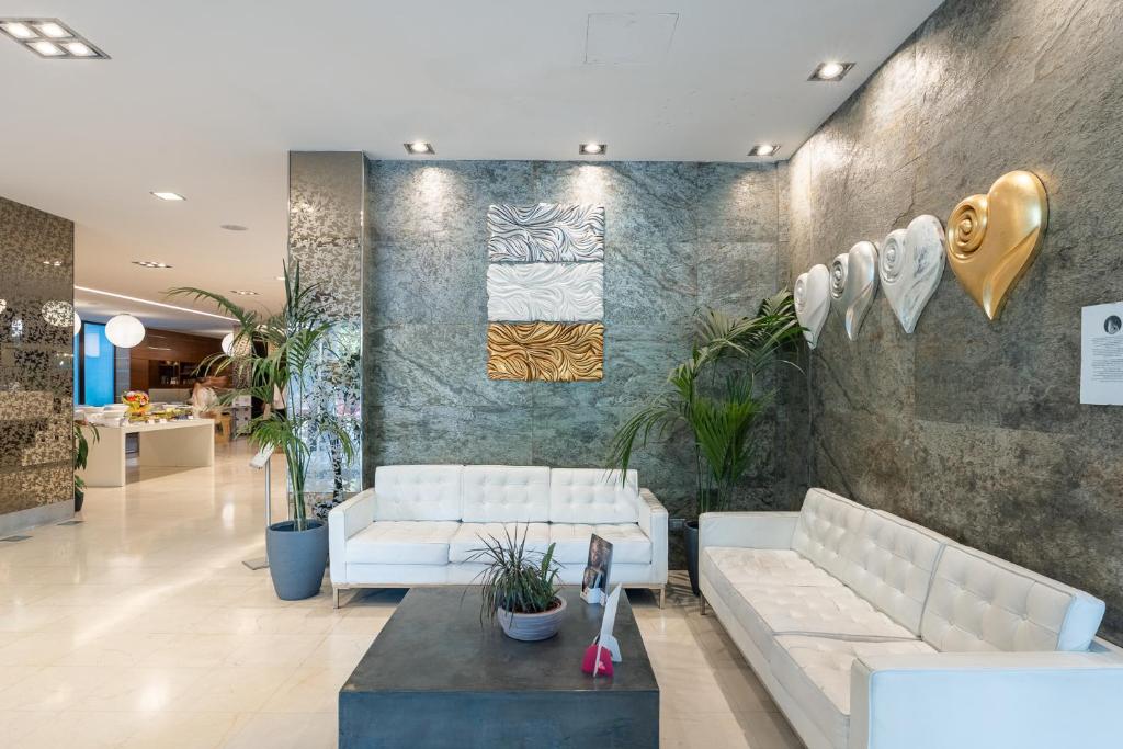 a lobby with white couches and plants on a wall at Smy Bologna Centrale in Bologna