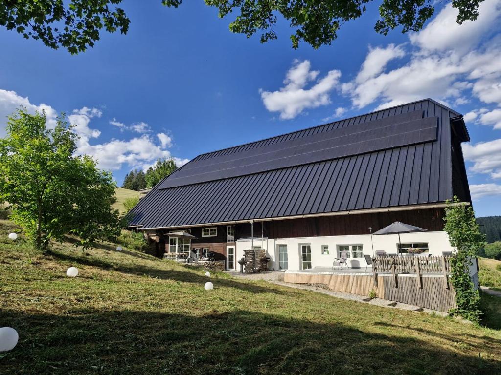 a barn with a black roof on a hill at Danielenhof1701, Ferienwohnung Bruckbach in Breitnau