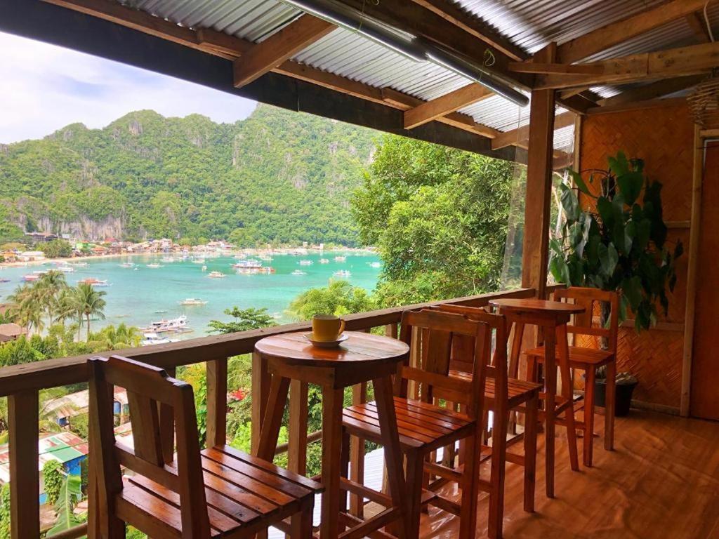 a balcony with chairs and a table and a view of the water at Bale Cabugao Cottages Rental El Nido overlooking Beach in El Nido