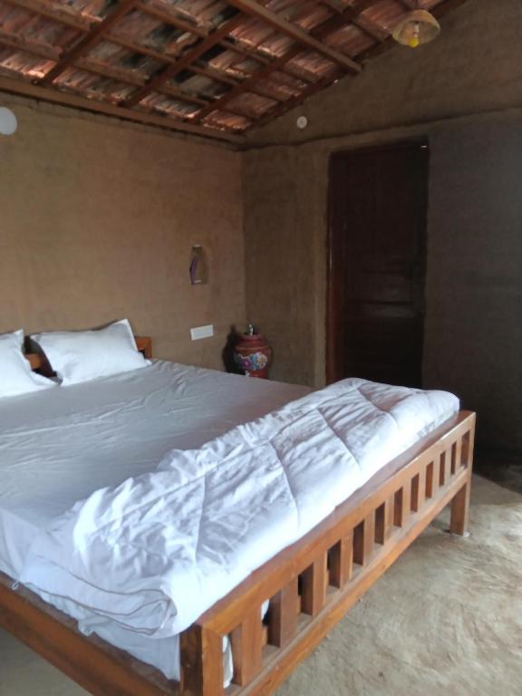 a bedroom with a wooden bed with white sheets at Ishika Homestay in Maheshwar