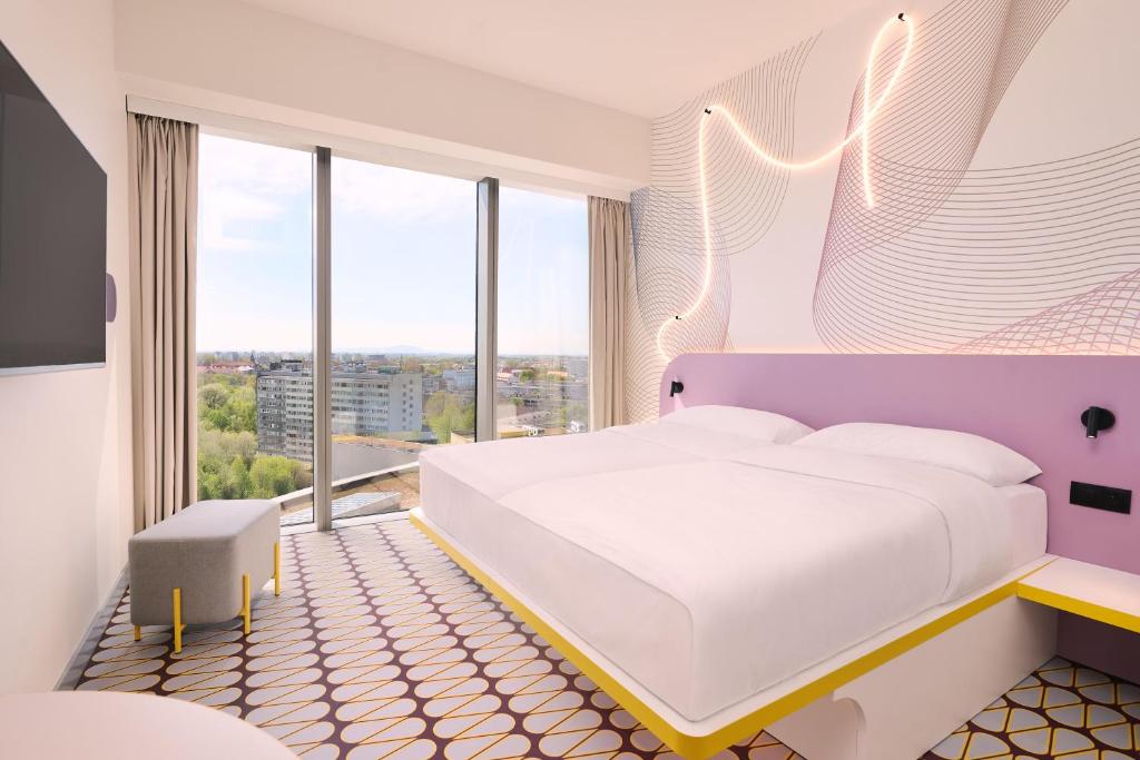 a bedroom with a white bed and large windows at Prize by Radisson, Wroclaw Sky Tower in Wrocław