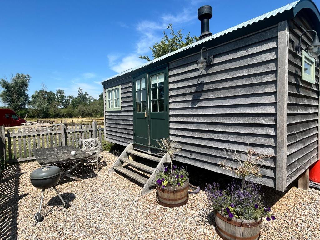 a tiny house with potted plants and a table at Astwell Mill Luxury Shepherds Hut in Helmdon