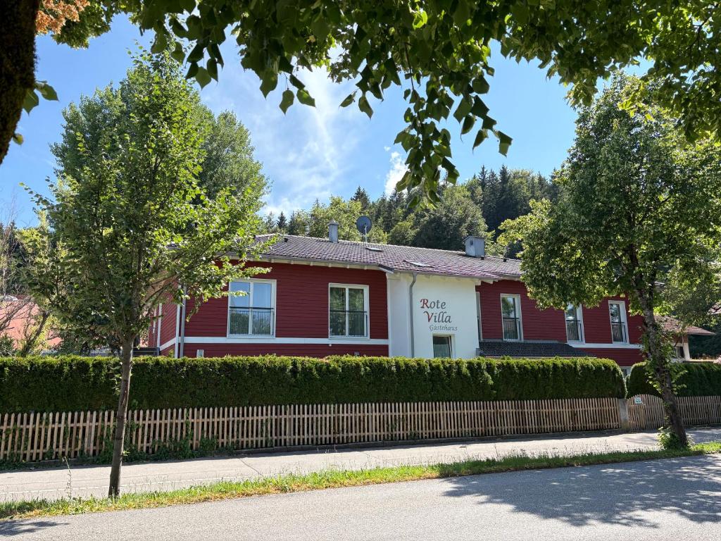 a red and white house with a fence and trees at Rote Villa Füssen in Füssen