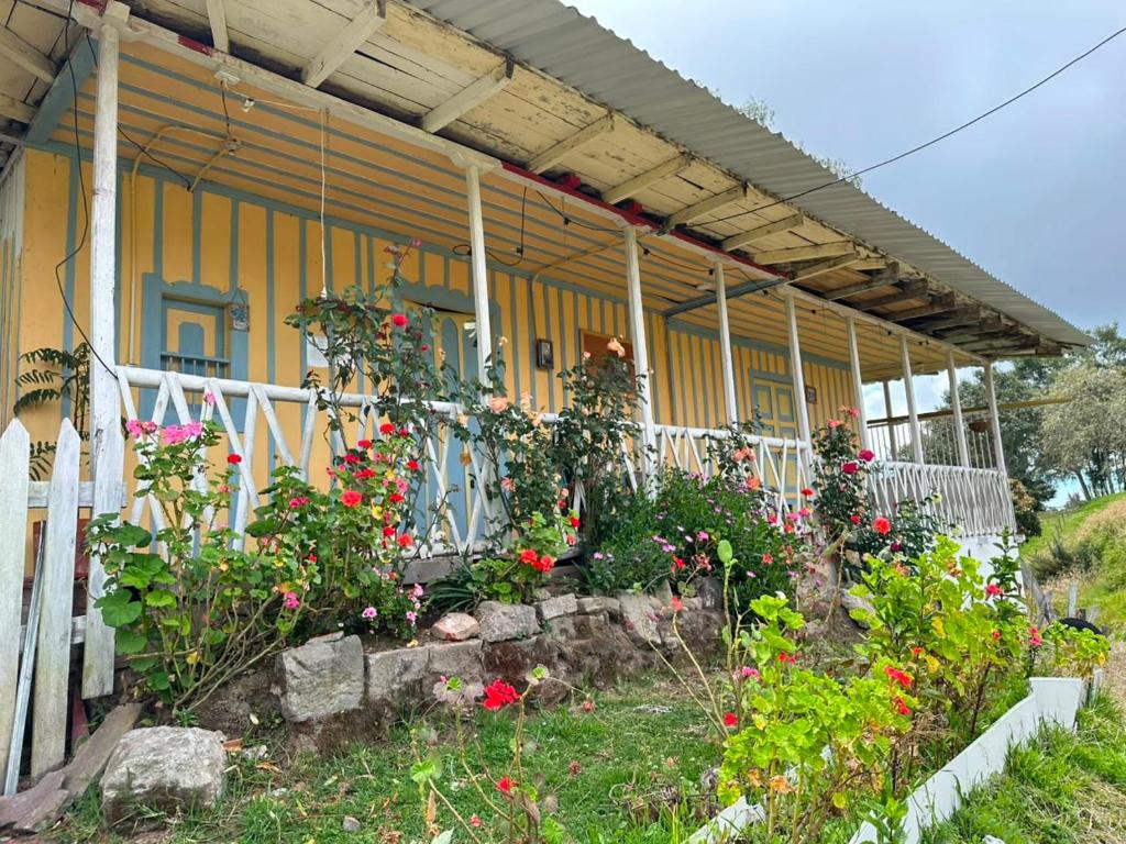 a yellow house with flowers in front of it at Refugio Paramo Trek Murillo in Murillo