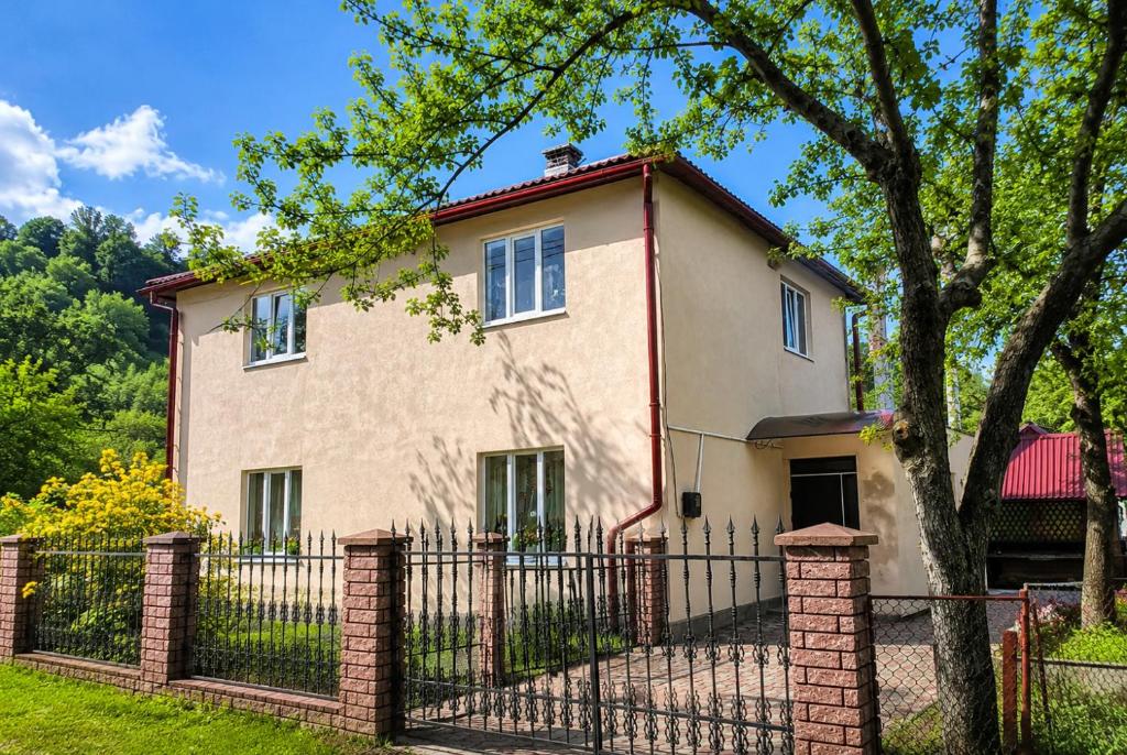 a house with a fence and a tree at Хостел в Карпатах in Yasinya