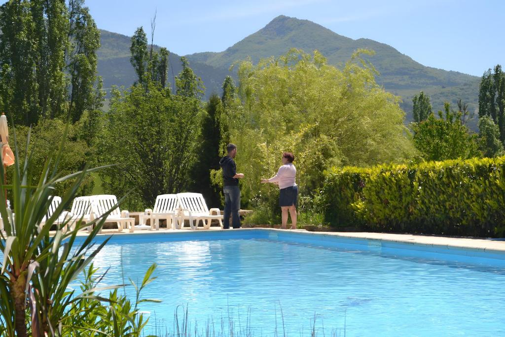 two people standing next to a swimming pool at Gite Des Sibourgs - Piscine & Clim in Bourdeaux