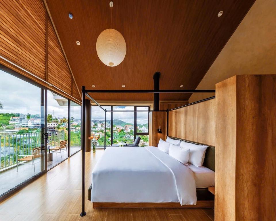a bedroom with a large bed and a large window at Là Yên Retreat in Ấp Ða Lợi