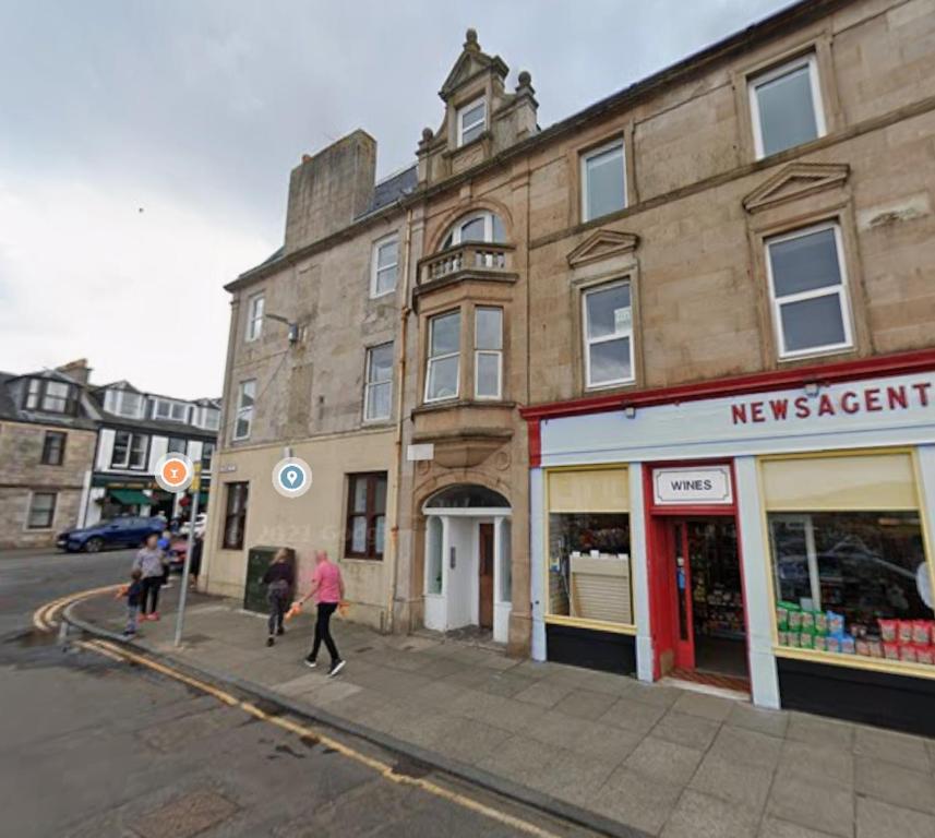 people walking down a street in front of a building at Wee Cumbrae View in Millport