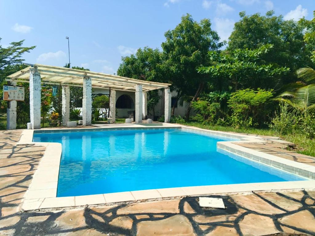 a swimming pool with a pergola and blue water at Fred Hunter Villa in Tiwi