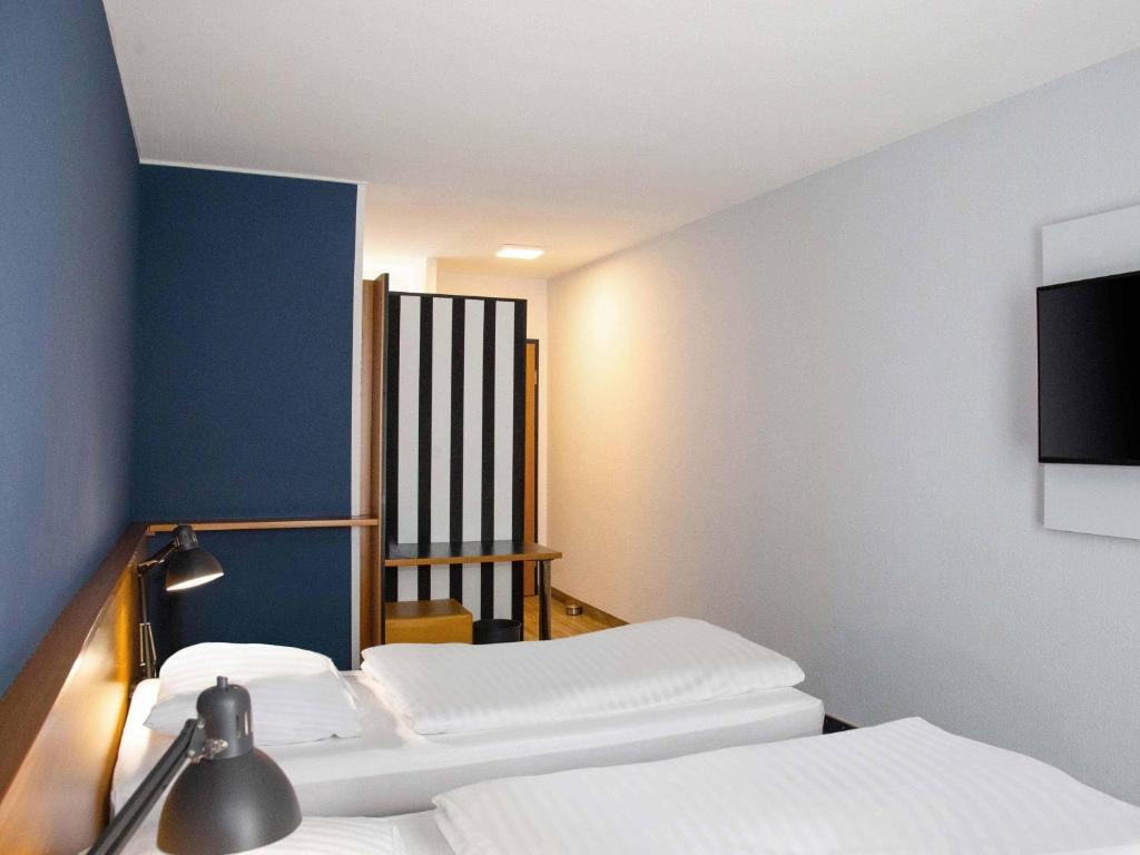 a room with three beds and a flat screen tv at B&B HOTEL Dresden-Altstadt in Dresden