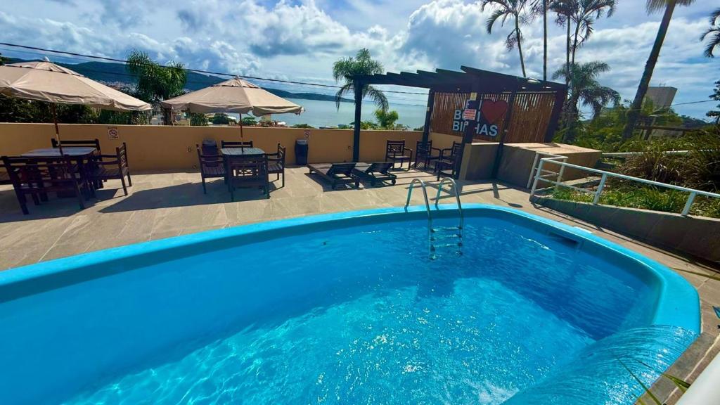 a large blue swimming pool with a table and chairs at Pousada Vila do Navegante in Bombinhas