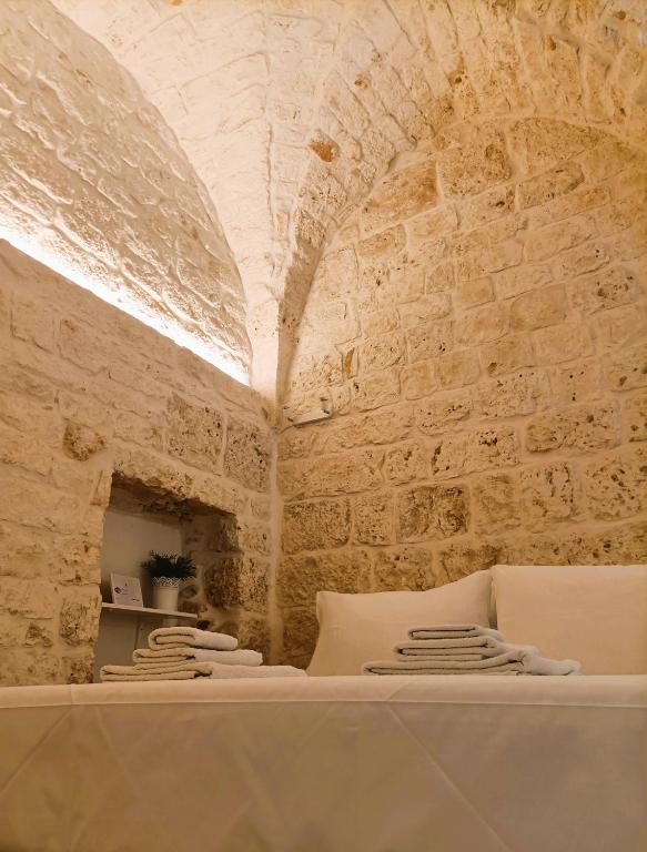 a room with white pillows and a stone wall at La Carruba in Ceglie Messapica
