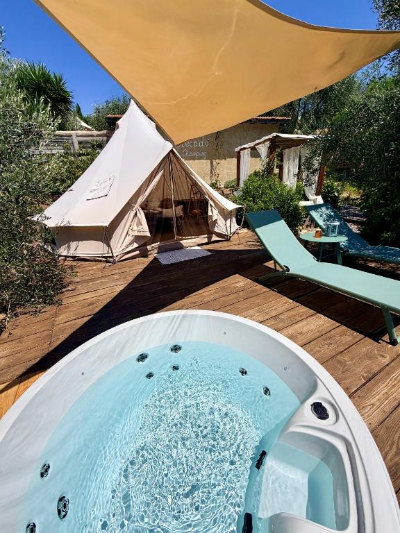a hot tub on a wooden deck with a tent at Stecadó Glamping in Dolceacqua