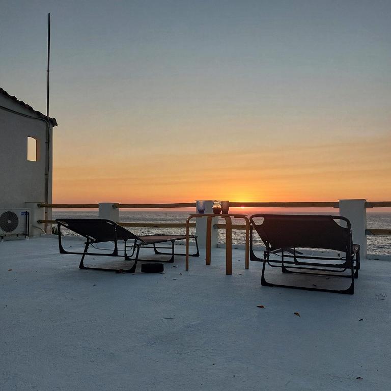 a table and chairs on the beach at sunset at Captain's View Guesthouse in Kouniádhoi