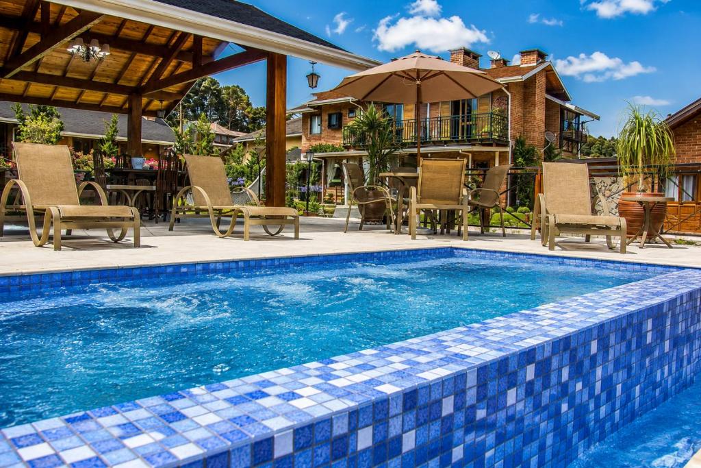 a swimming pool with chairs and a house at Pousada Charme da Montanha in Monte Verde