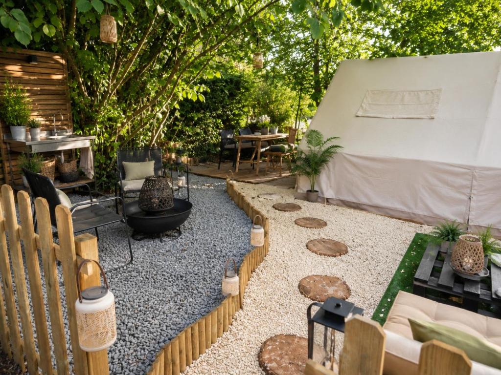 a backyard with a fire pit and a fence at THOUARS Rivière LODGE KAËLI in Maulais