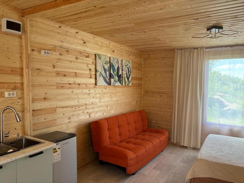 a kitchen with an orange couch in a room at Экохаус Hemingway 1 in Borovoye