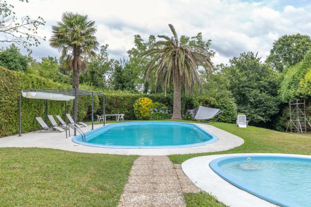 a swimming pool in a yard with two palm trees at Cabañita rústica con piscinas in Cambre