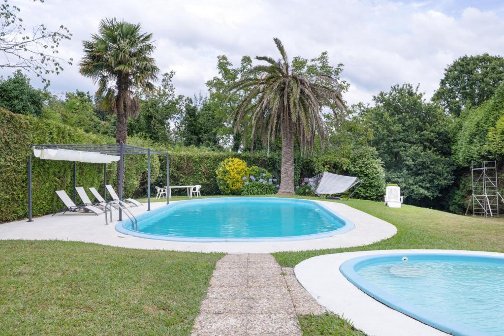 a swimming pool in a yard with two palm trees at Acogedor chalet rústico in Cambre