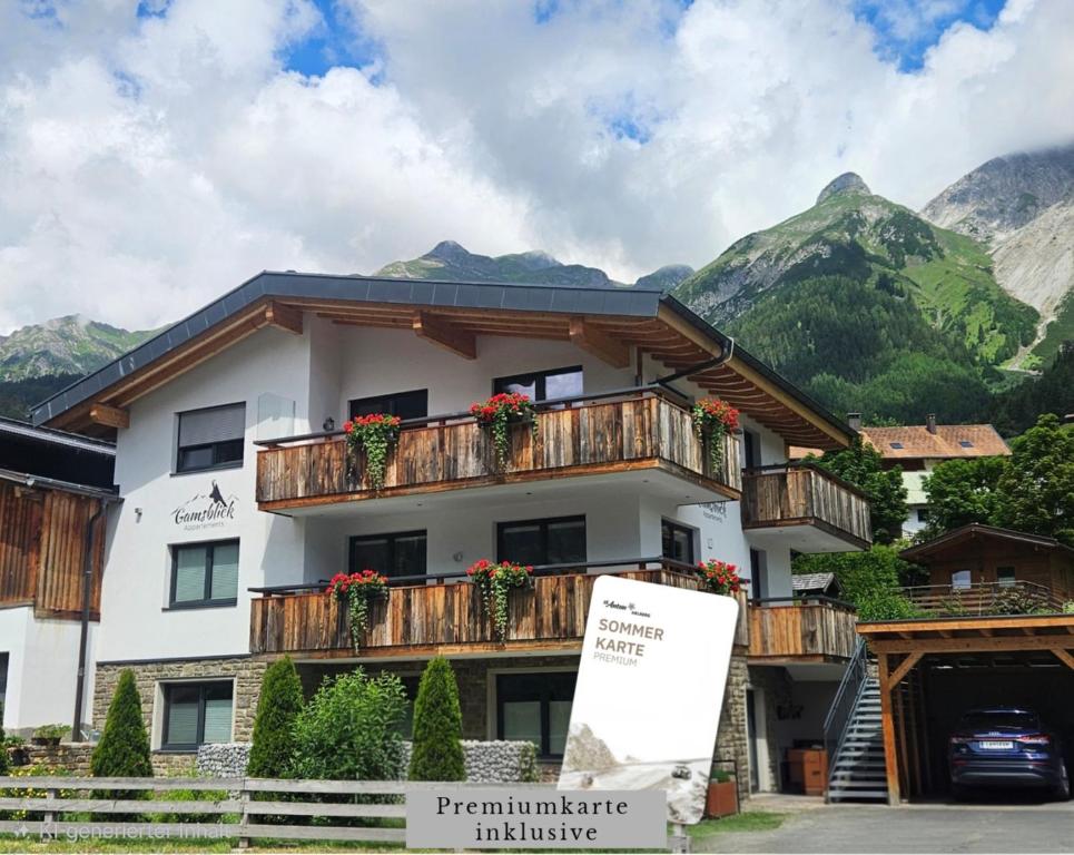 a building with flowers on the balconies in front of mountains at Appartements Gamsblick in Pettneu am Arlberg