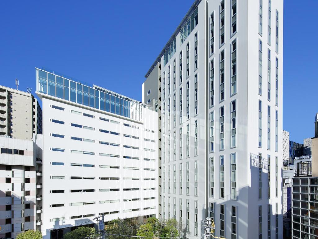 a tall white office building in a city at Shinjuku Granbell Hotel in Tokyo